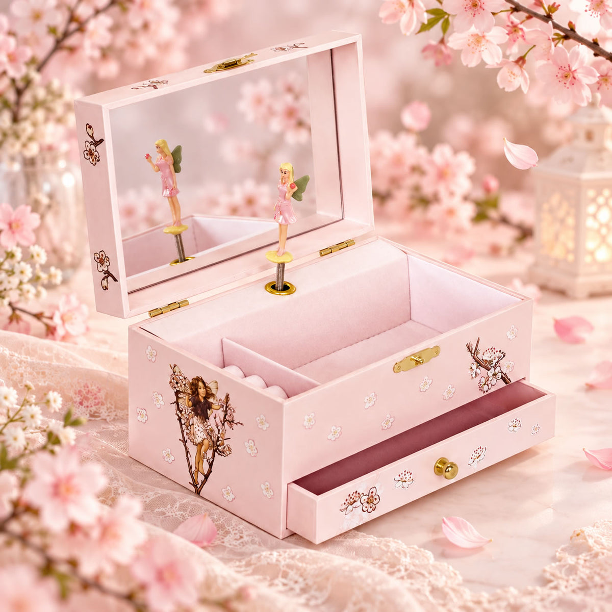 A pink wooden jewelry box with an open lid, decorated with floral prints, rhinestones, and small figurines, set against a soft background of pink blossoms and lace.